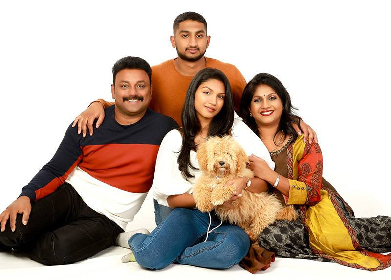 Relaxed studio session: family of four sitting together on a white backdrop with their fluffy dog