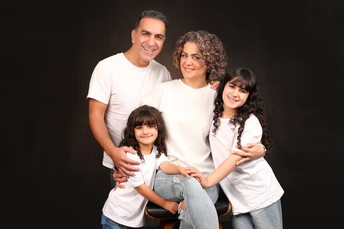 Family of four in white tees, dark studio portrait