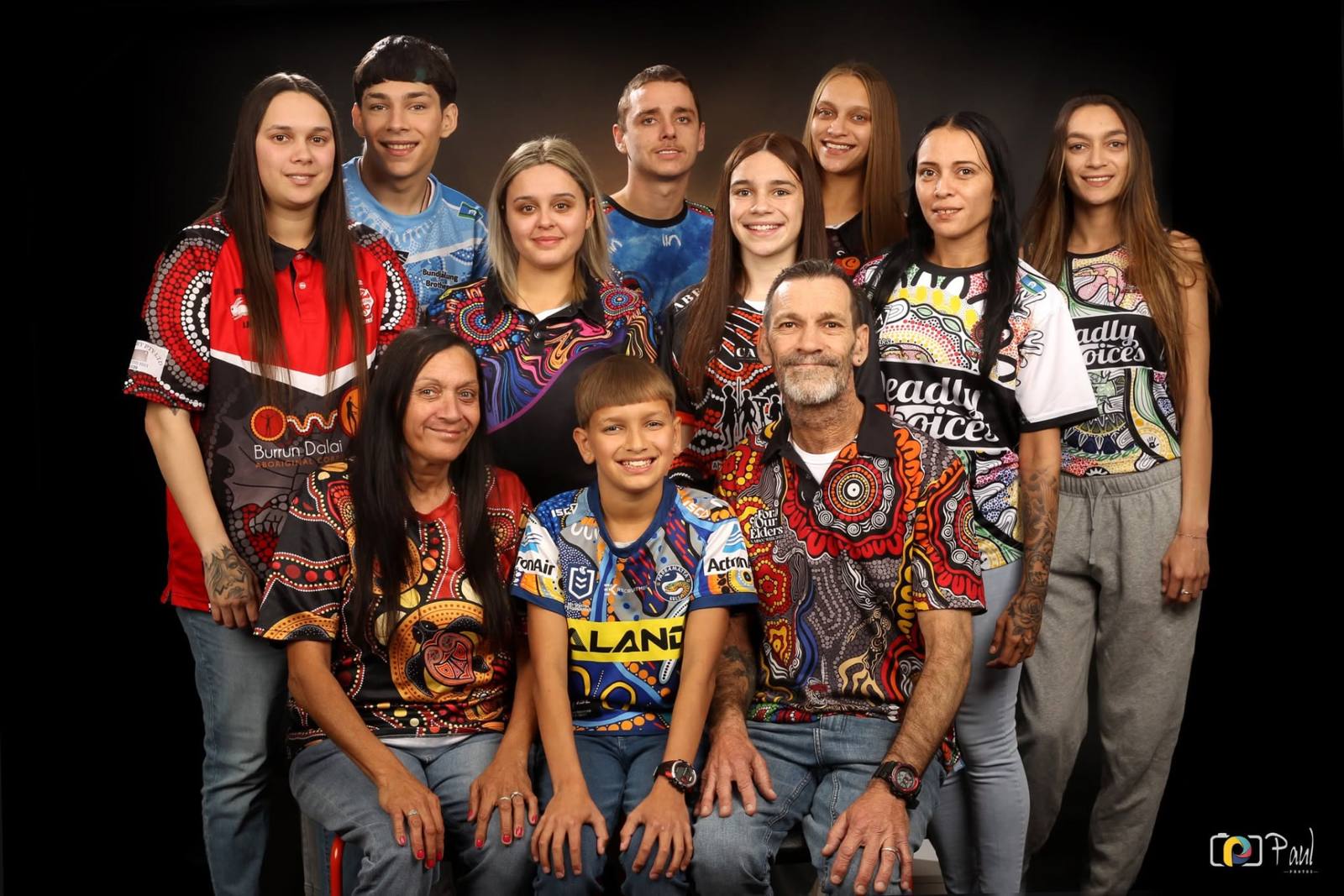 Large extended family in colourful jerseys photographed in Paul Photos' Sydney studio