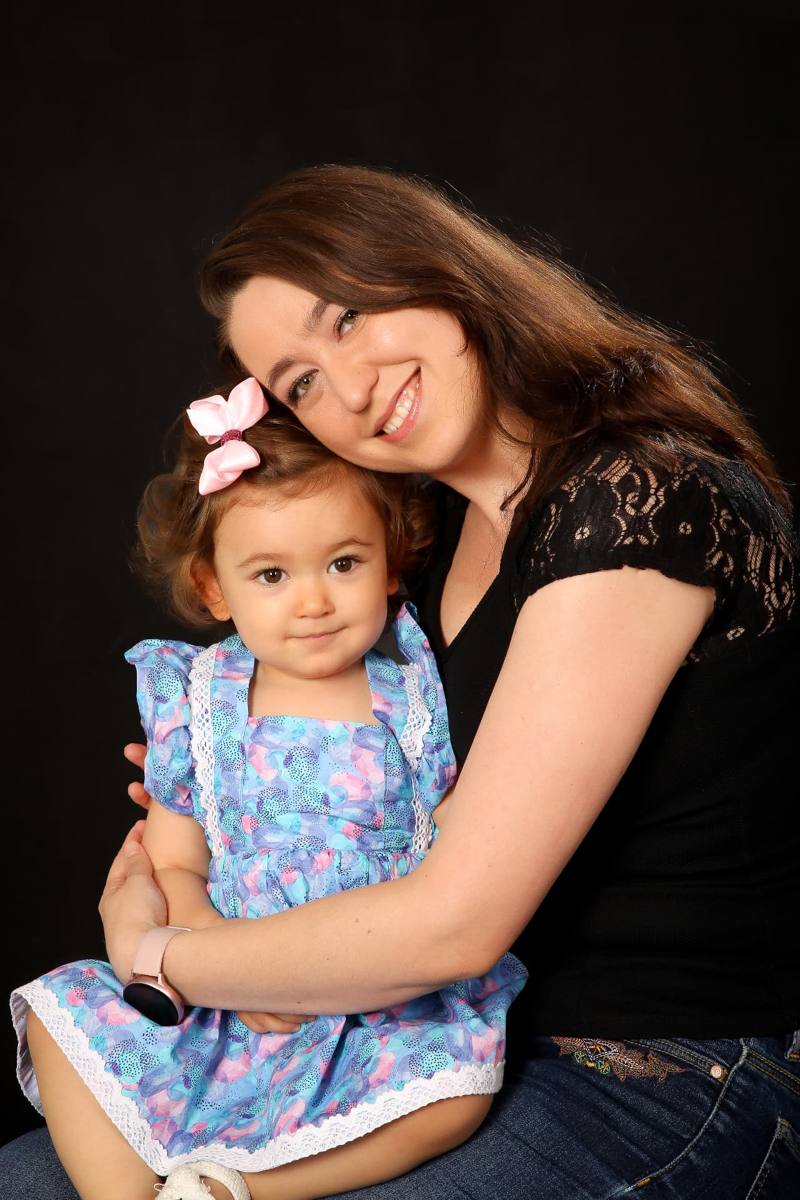 Mum hugging her toddler daughter, studio portrait